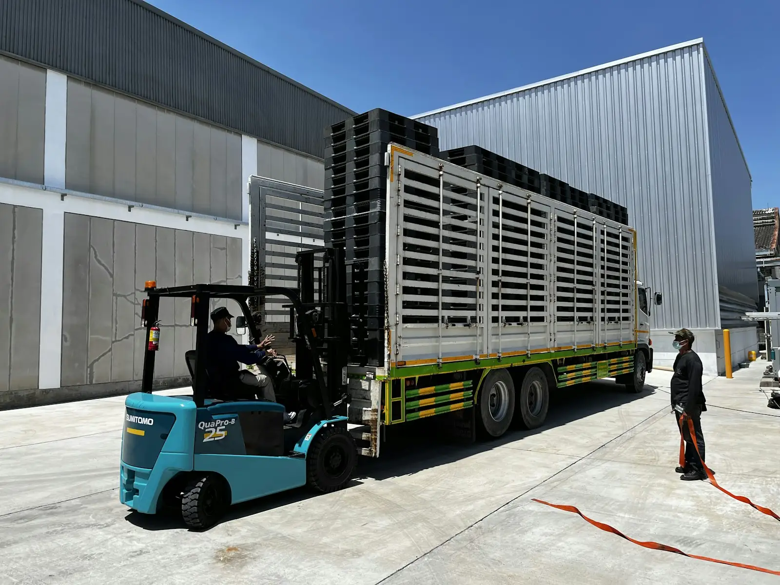 A forklift loading pallets of goods onto a truck at a warehouse.